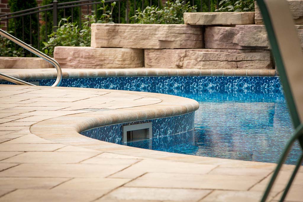 offwhite coping on blue walled pool with stone slabs in background
